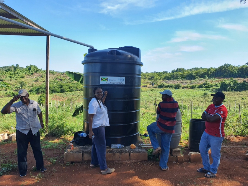 People standing around a large black water tank.
