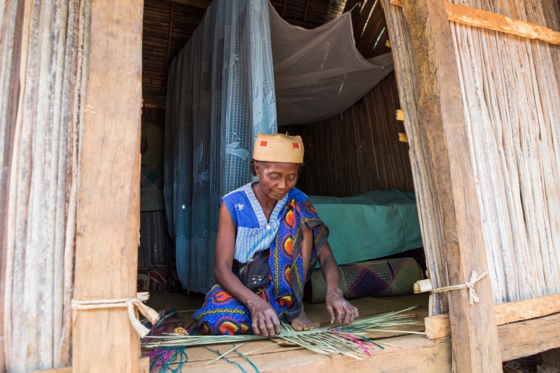 Woman weaving in the doorway of her home
