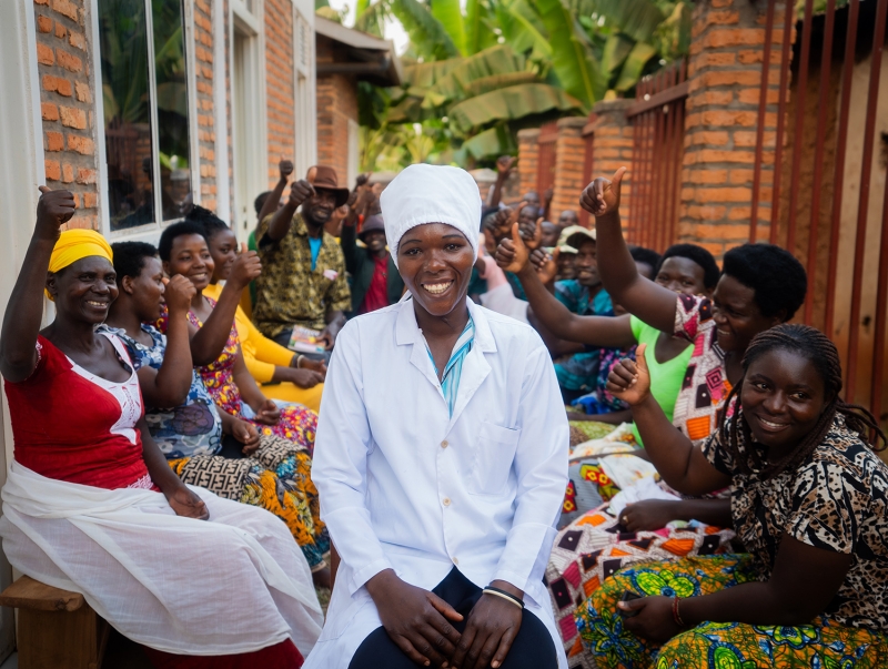 A woman in sitting with other women, smiling at the camera
